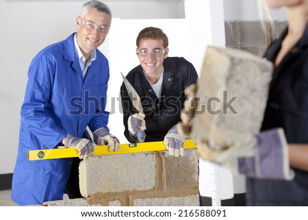 Teacher talking to student using level in bricklaying vocational school