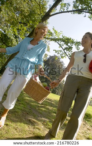 Two women carrying a picnic basket.
