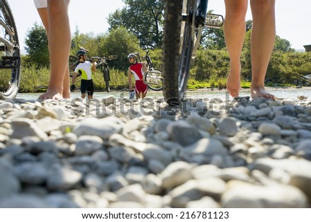 Friends walking on pebbles with their cycles.