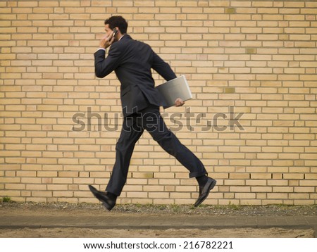 A businessman running and talking on his mobile phone.