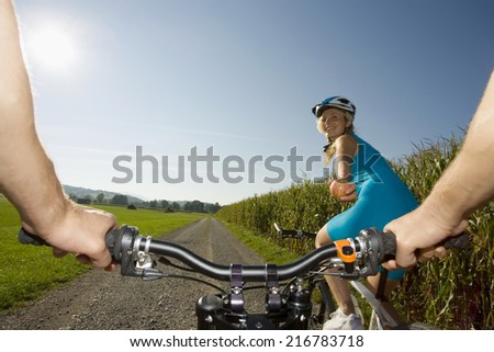 A woman giving her friend an apple while cycling.