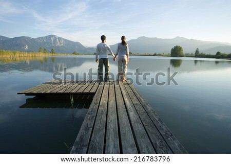 A couple standing at the end of a pier.