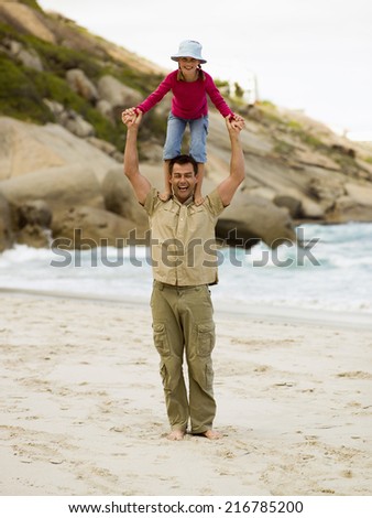 A father carrying with his daughter on his shoulders.