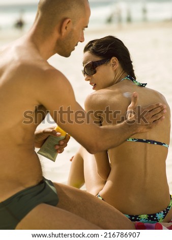 Man applying suntan lotion on his girlfriend.