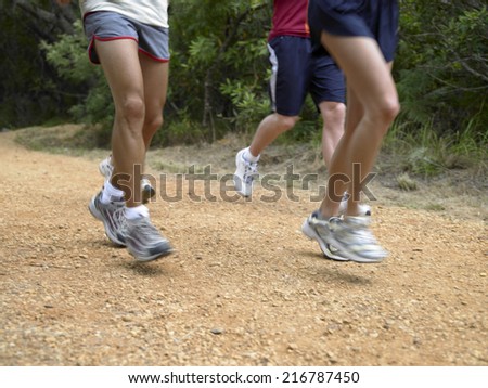 Low section view of two men and a woman running