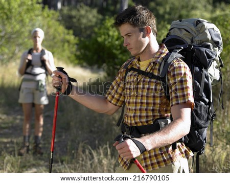 Close-up of a young man hiking and a young woman standing in background