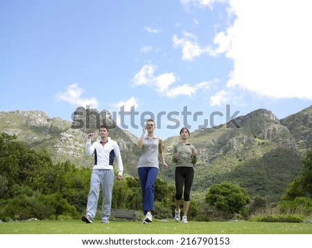 Low angle view of two young women and a young man jogging
