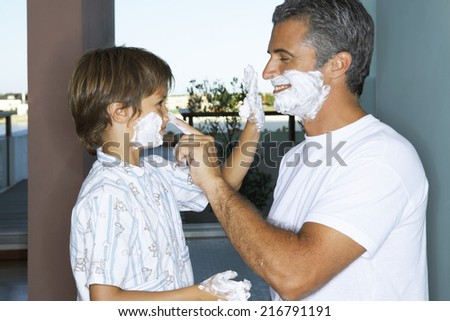 Father and son applying shaving foam.