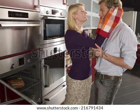 Side profile of a young woman holding a young man's face with oven mitts