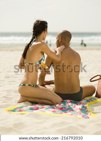 Woman applying suntan lotion on her boyfriend.