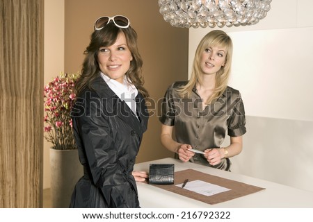 Close-up of a woman standing at a checkout counter with a receptionist