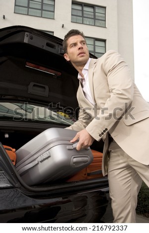 Man taking a luggage from a car trunk