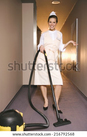 Portrait of a maid cleaning the floor with a vacuum cleaner