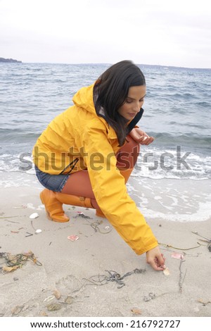 Young woman crouching on the beach and collecting shells