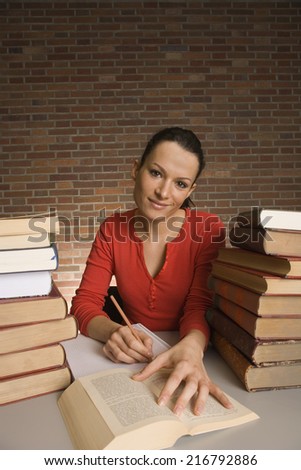 Portrait of a young woman writing with a pencil in a notepad