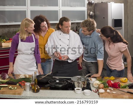 Male Chef teaching four students in the kitchen