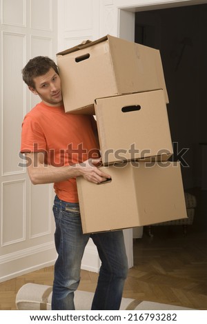 Portrait of a young man carrying cardboard boxes
