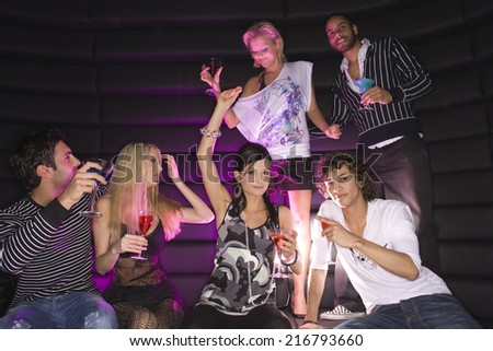 Young couple dancing in a nightclub with their friends having drinks
