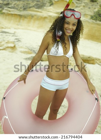 Portrait of a young woman holding a life belt on the beach
