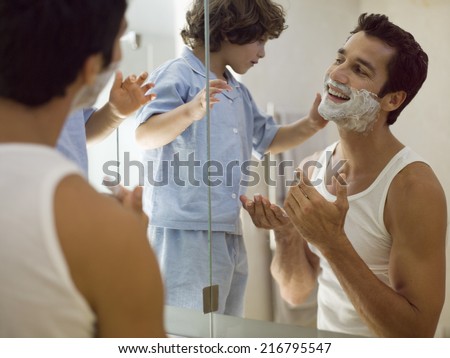Boy applying shaving foam on his father.