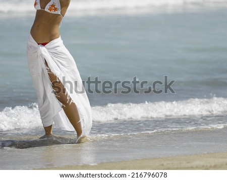 Low section view of a mid adult woman standing on the beach