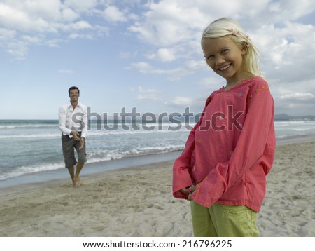 Portrait of a girl smiling with her father standing in the background