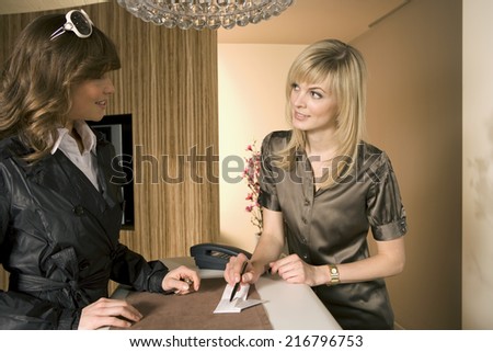 Close-up of a woman standing at a checkout counter with a receptionist