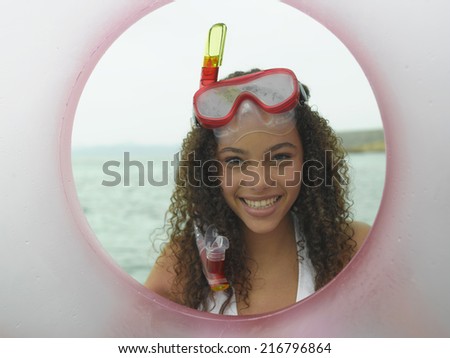 Portrait of a young woman smiling and looking through a life belt