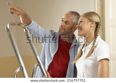 Side profile of a young woman smiling with a mid adult man pointing upward