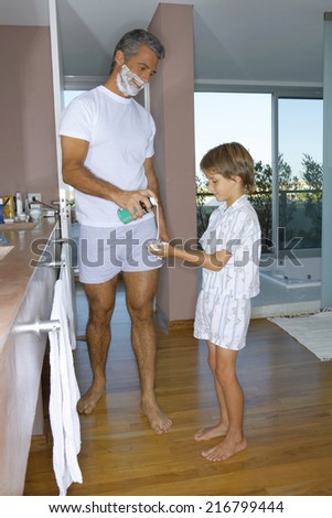 Father giving son shaving foam.