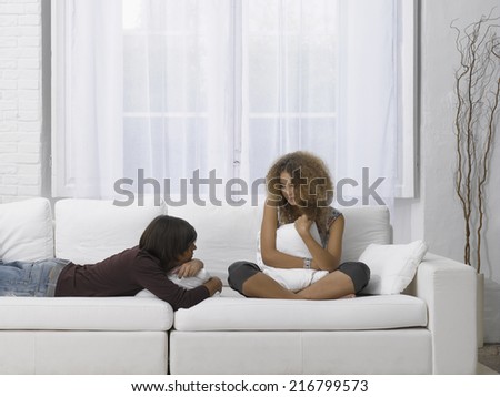 Side profile of a young man lying on a couch with a young woman sitting beside him