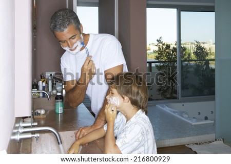 Father and son shaving in the bathroom.