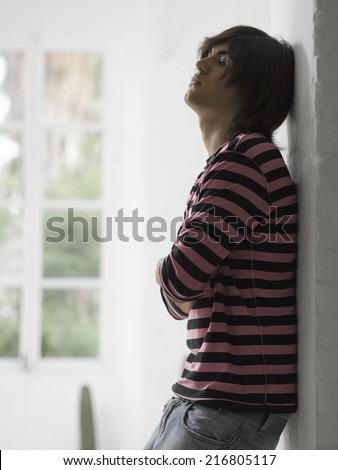 Side profile of a young man leaning against a wall