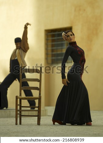 Side profile of a female dancer dancing with a young man in the background