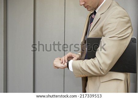 Side profile of a businessman looking at his wrist watch