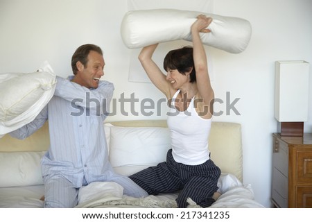 Mature couple having a pillow fight on the bed