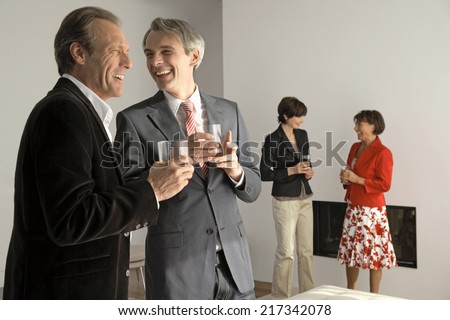 Two men holding wine glasses with two women standing in background