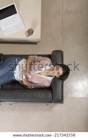 View from above of woman laying on couch smiling