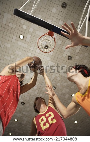 Low angle view of three young men playing basketball