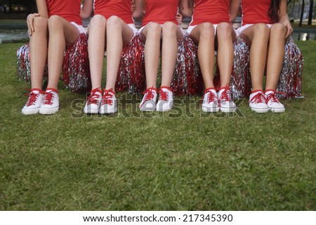 Low section view of five cheerleaders sitting side by side