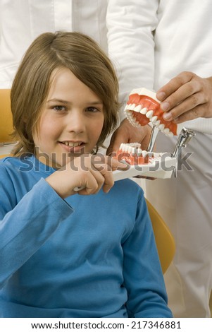 Dental assistant teaching a boy how to brush teeth