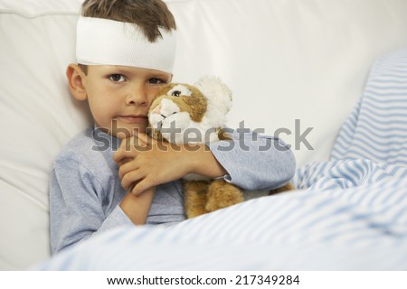 Portrait of a boy hugging a stuffed toy with a bandage on his forehead