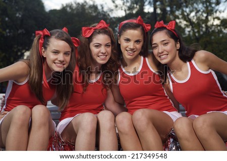 Portrait of four cheerleaders side by side and smiling