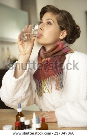 Side profile of a mid adult woman drinking a glass of water after her medicine