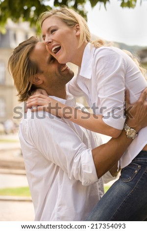 Side profile of a young man picking up a young woman and smiling