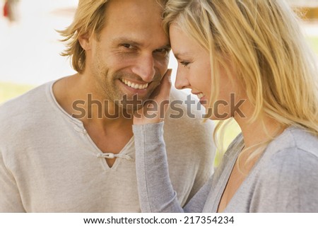 Side profile of a young woman touching a young man\'s face and smiling