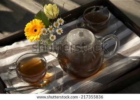 High angle view of a cup of tea and a teapot set with a flower vase on a tray
