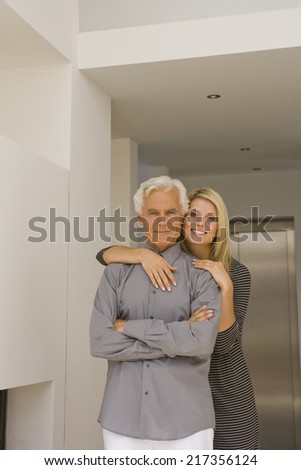 Portrait of a young woman embracing a senior man from behind and smiling
