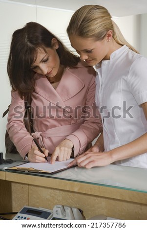 Young woman standing with a nurse and filling a form