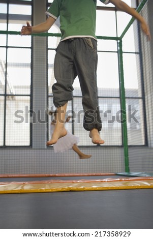 Low section view of a boy with a girl jumping on a trampoline